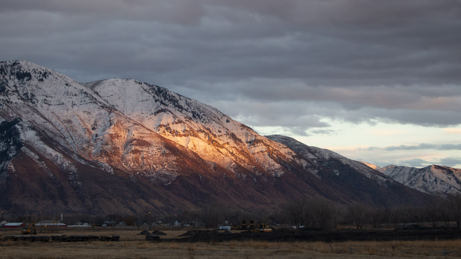 the mountain is lit red-orange in a big spot by the setting sun